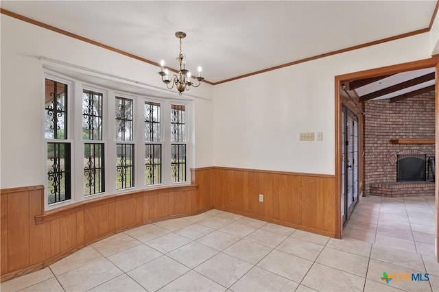 unfurnished dining area featuring an inviting chandelier, ornamental molding, vaulted ceiling, a brick fireplace, and light tile patterned floors