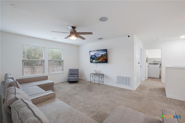 living room featuring ceiling fan, light colored carpet, and washer / dryer