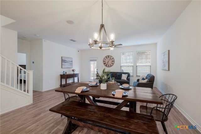 dining space with light hardwood / wood-style floors and ceiling fan with notable chandelier