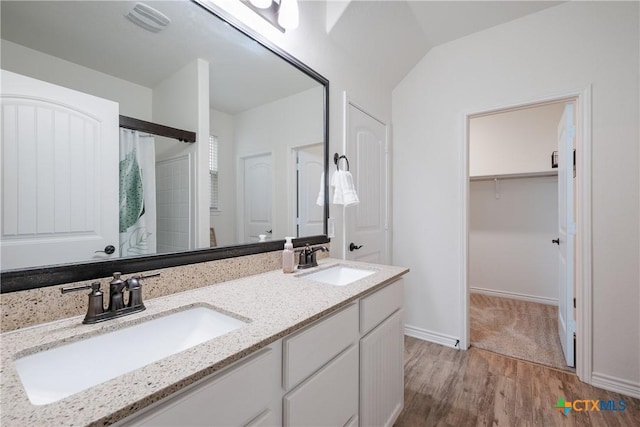 bathroom with hardwood / wood-style floors, vanity, vaulted ceiling, and walk in shower