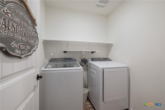 laundry room with wood-type flooring and washer and clothes dryer