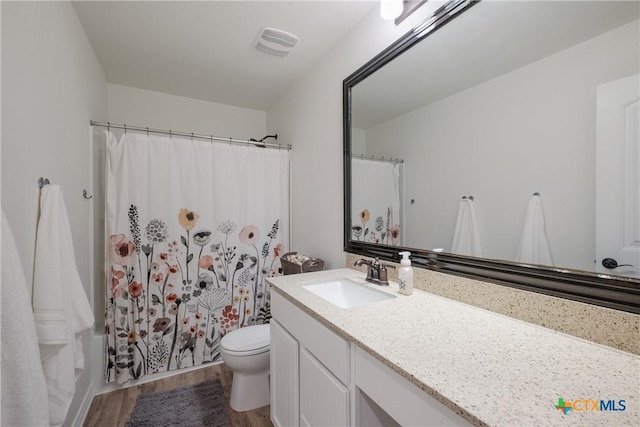 full bathroom featuring vanity, hardwood / wood-style flooring, toilet, and shower / tub combo with curtain