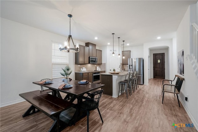 dining space featuring a chandelier, light hardwood / wood-style flooring, and sink