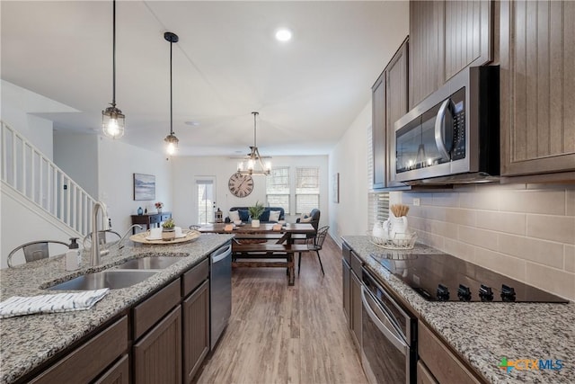 kitchen featuring pendant lighting, sink, appliances with stainless steel finishes, light hardwood / wood-style floors, and light stone counters