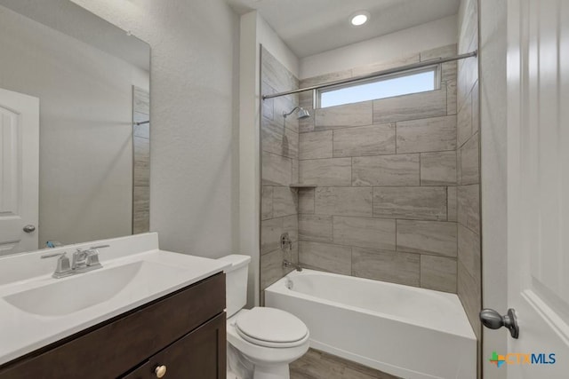 full bathroom featuring vanity, tiled shower / bath combo, wood-type flooring, and toilet