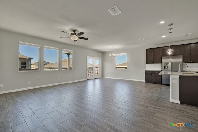 unfurnished living room with dark wood-type flooring, sink, and ceiling fan with notable chandelier