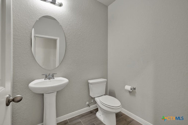 bathroom featuring wood-type flooring, toilet, and sink