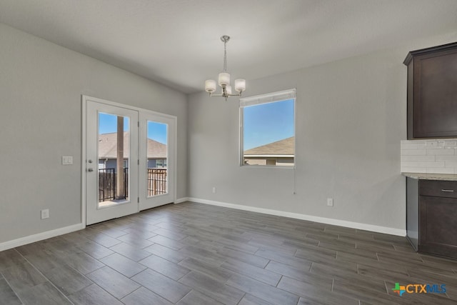 unfurnished dining area with dark wood-type flooring and a notable chandelier