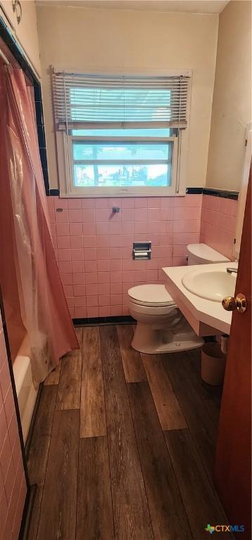 3605 Oaklawn St, Victoria, TX 77901 - full bath featuring tile walls, wood-type flooring, a wainscoted wall, and shower / tub combo with curtain