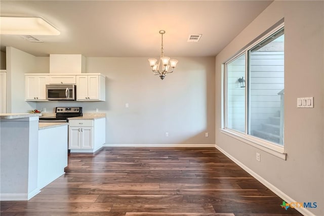 kitchen featuring appliances with stainless steel finishes, dark hardwood / wood-style floors, pendant lighting, white cabinets, and a notable chandelier