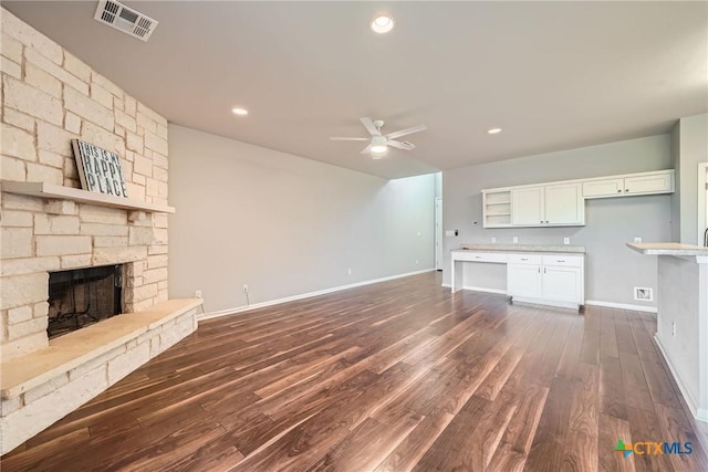 unfurnished living room featuring dark wood-type flooring, ceiling fan, and a fireplace