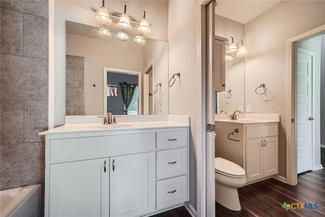 bathroom with wood-type flooring, a bathing tub, vanity, and toilet