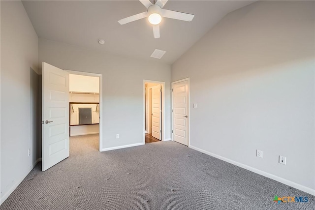 unfurnished bedroom featuring ceiling fan, a walk in closet, vaulted ceiling, and carpet flooring