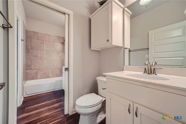 full bathroom featuring hardwood / wood-style flooring, vanity, toilet, and tiled shower / bath combo