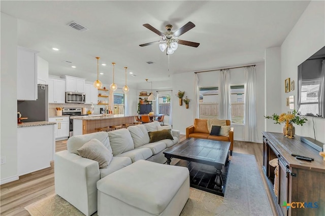 living room with ceiling fan and light hardwood / wood-style flooring