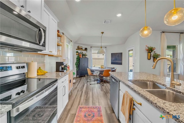 kitchen featuring sink, hanging light fixtures, light wood-type flooring, stainless steel appliances, and white cabinets