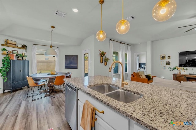 kitchen with sink, hanging light fixtures, light wood-type flooring, stainless steel dishwasher, and white cabinets