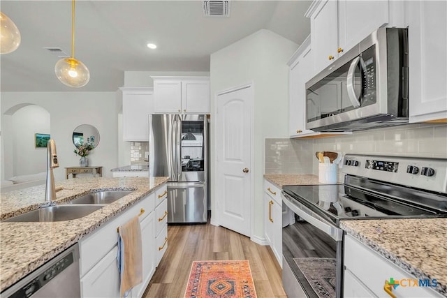 kitchen featuring appliances with stainless steel finishes, sink, white cabinets, and decorative light fixtures