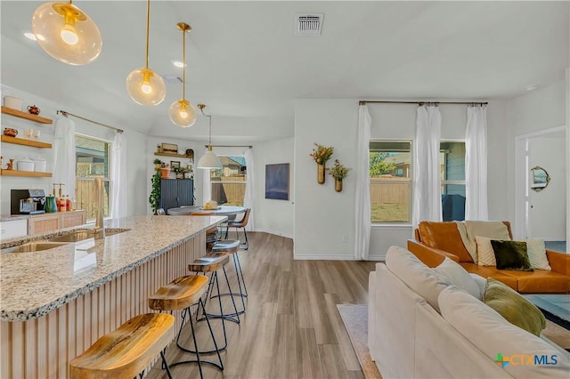 living room featuring plenty of natural light, sink, and light hardwood / wood-style flooring