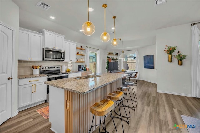 kitchen with white cabinetry, appliances with stainless steel finishes, a kitchen island with sink, and sink