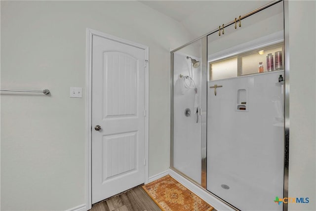 bathroom with hardwood / wood-style flooring and a shower with shower door