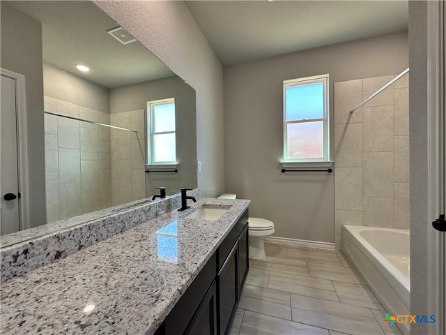 full bathroom with vanity, plenty of natural light, tiled shower / bath, and toilet