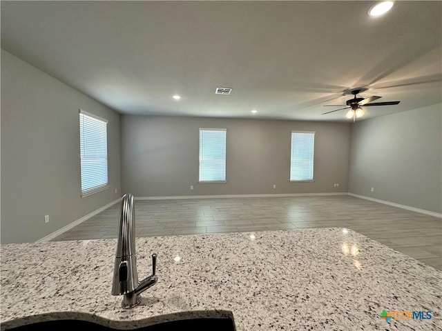 kitchen with light stone countertops, plenty of natural light, sink, and ceiling fan