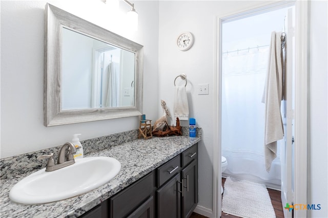 bathroom with hardwood / wood-style floors, a shower with shower curtain, vanity, and toilet