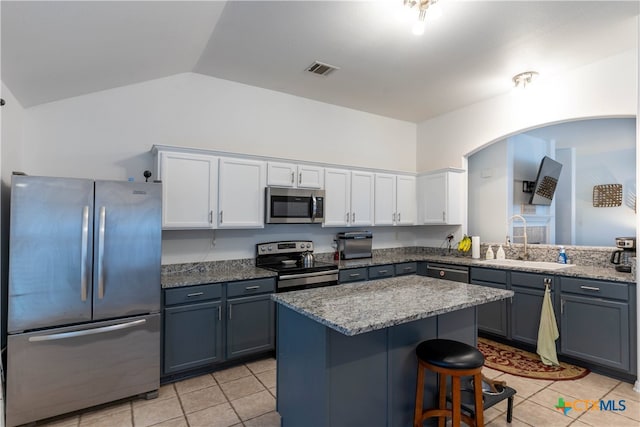 kitchen with white cabinetry, appliances with stainless steel finishes, sink, vaulted ceiling, and a breakfast bar area