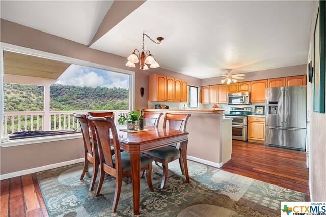 dining space with ceiling fan with notable chandelier and dark hardwood / wood-style flooring