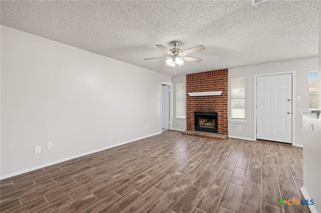 unfurnished living room with a ceiling fan, a brick fireplace, wood finished floors, and baseboards