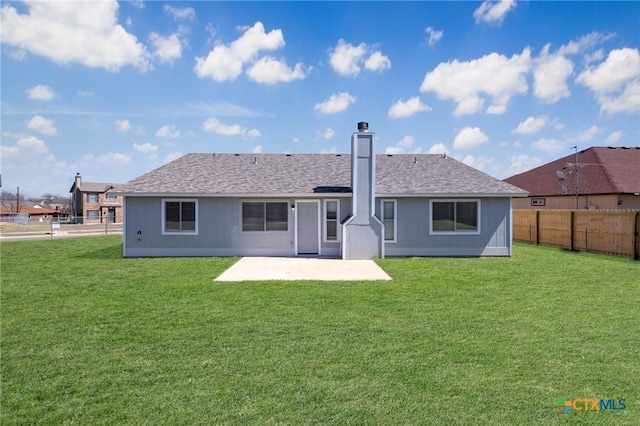 rear view of property featuring a yard, a shingled roof, a patio, and fence