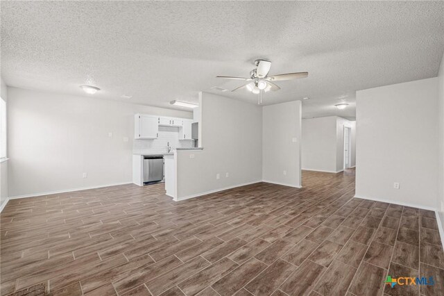 unfurnished living room with a sink, baseboards, ceiling fan, and wood finished floors