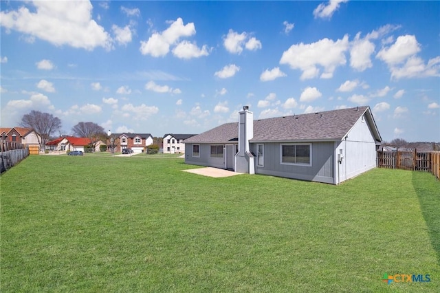 back of house with a lawn, a fenced backyard, a residential view, roof with shingles, and a chimney