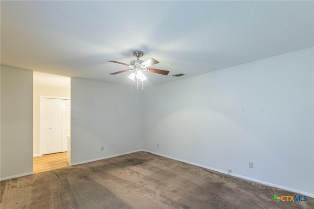 carpeted spare room with visible vents, ceiling fan, and baseboards