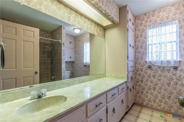 bathroom featuring tiled shower, toilet, and wallpapered walls