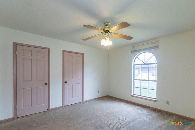 unfurnished bedroom with light carpet, baseboards, and a ceiling fan