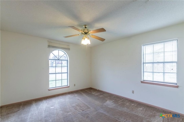 empty room featuring a textured ceiling, ceiling fan, carpet flooring, and baseboards