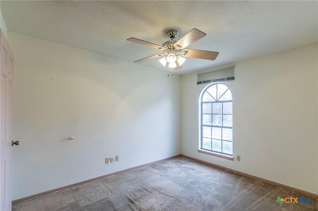 carpeted empty room with ceiling fan, baseboards, and a textured ceiling