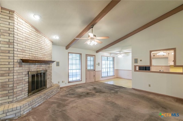 unfurnished living room with carpet, wainscoting, a fireplace, and vaulted ceiling with beams