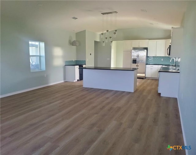 1211 W Houson Ave, Seadrift, TX 77983 - kitchen featuring dark countertops, a kitchen island, stainless steel fridge with ice dispenser, white cabinets, and a sink
