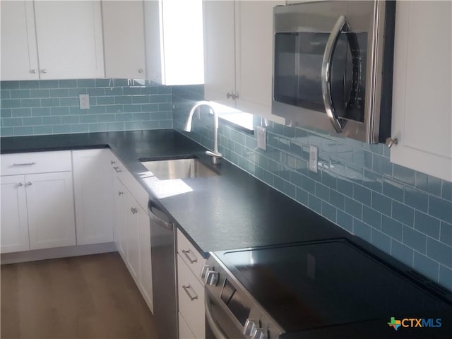 1211 W Houson Ave, Seadrift, TX 77983 - kitchen featuring a sink, stainless steel appliances, backsplash, and white cabinetry