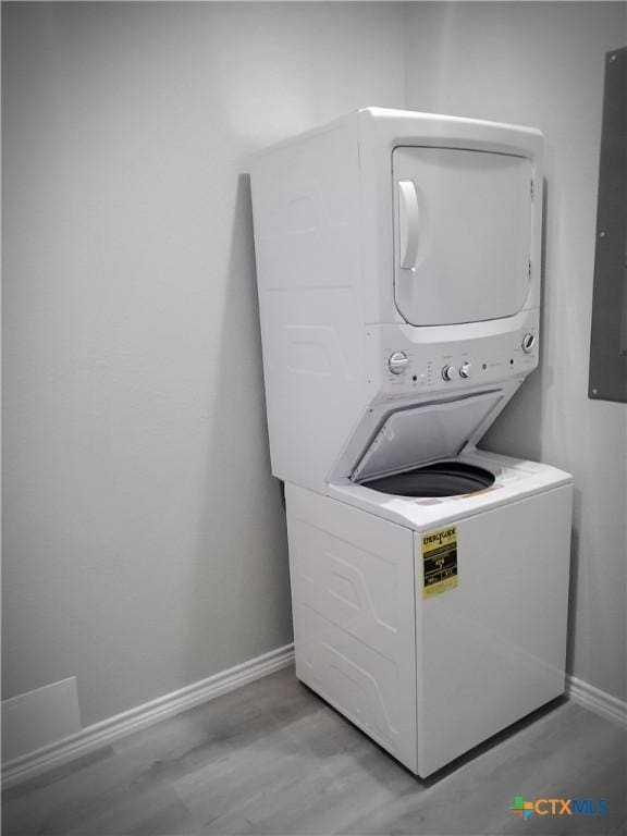 1211 W Houson Ave, Seadrift, TX 77983 - clothes washing area with baseboards, laundry area, light wood-style flooring, electric panel, and stacked washer / drying machine
