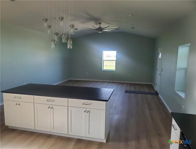 1211 W Houson Ave, Seadrift, TX 77983 - kitchen with dark countertops, lofted ceiling, wood finished floors, white cabinets, and a ceiling fan