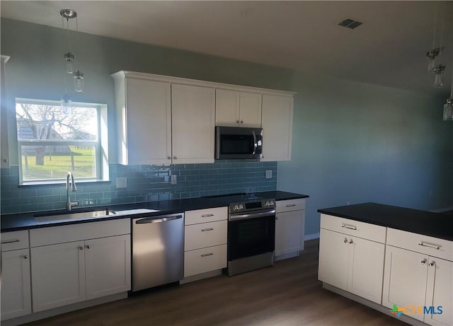 1211 W Houson Ave, Seadrift, TX 77983 - kitchen with visible vents, a sink, dark countertops, stainless steel appliances, and decorative backsplash
