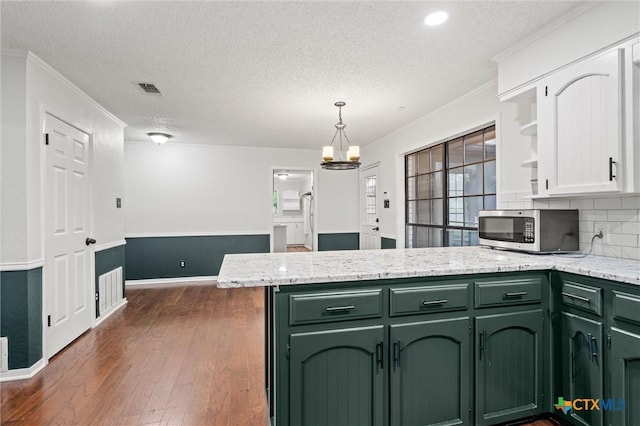 4101 Briar Cliff Rd, Temple, TX 76502 - kitchen with green cabinetry, stainless steel microwave, a peninsula, a textured ceiling, and dark wood-type flooring