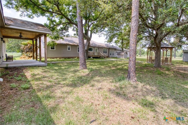 view of yard with a wooden deck and ceiling fan