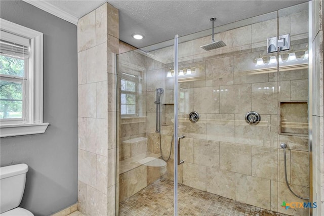 bathroom with a textured ceiling, toilet, ornamental molding, and walk in shower