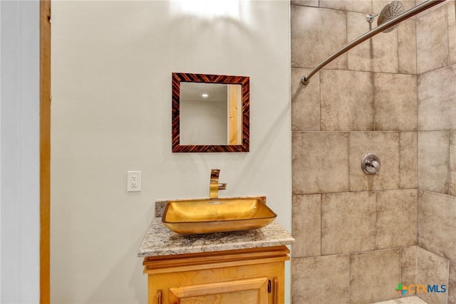 bathroom with a tile shower and vanity