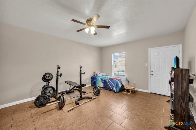 exercise area featuring ceiling fan and a textured ceiling